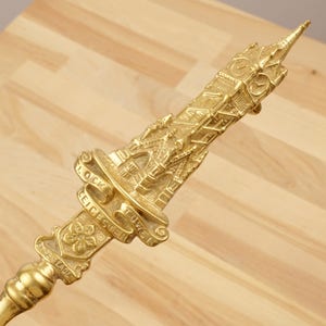 Peut inclure: Un tisonnier en m&eacute;tal dor&eacute; avec un design d&eacute;taill&eacute; d'une tour de ch&acirc;teau. Le tisonnier porte les inscriptions "Tower Leicester" et "Clock".