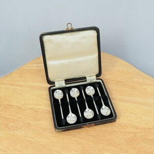 May include: A set of six silver teaspoons with black handles, in a black velvet lined box.