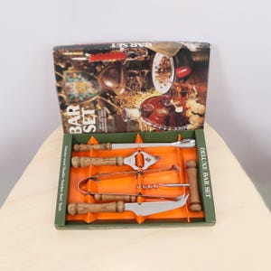 May include: A deluxe bar set with stainless steel tools and genuine wood handles. The set includes a bottle opener, corkscrew, knife, and other bar accessories. The box features the words "BAR SET" and "DELUXE BAR SET".