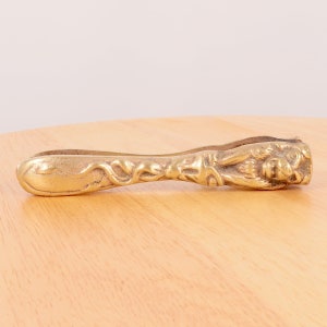 以下が含まれることがあります： ハンドルにライオンの頭部の詳細なデザインが施された、金色の真鍮製のナッツクラッカーです。