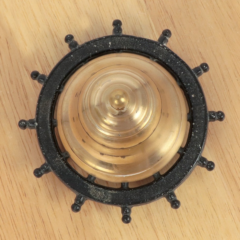 May include: A black and gold ship's wheel shaped doorbell with a brass bell.