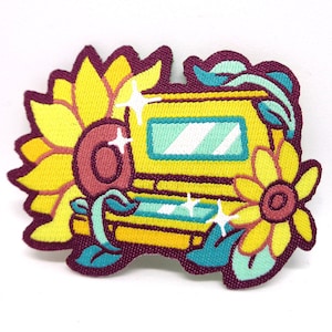 Puede incluir: Parche bordado amarillo con una consola de juegos amarilla y verde rodeada de girasoles y hojas. La consola tiene una pantalla azul y un botón rosa.