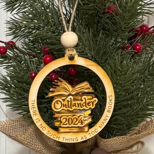May include: A wooden Christmas ornament with a stack of books and the text "Outlander 2024" and "There is no such thing as too many books".