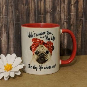 Peut inclure: Mug en c&eacute;ramique blanche avec int&eacute;rieur et anse rouges. Le mug repr&eacute;sente un carlin portant un bandana rouge &agrave; pois, avec le texte "I didn't choose the Pug Life. The Pug life chose me !" Une marguerite en papier blanc est &agrave; gauche.