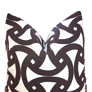 May include: A white pillow with a brown geometric pattern. The pattern is made up of interlocking circles and squares.