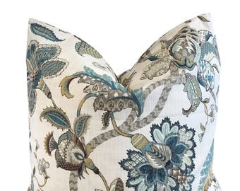 May include: A white pillow with a floral pattern in shades of teal, brown, and gold. The pillow has a square shape and a soft, textured fabric.