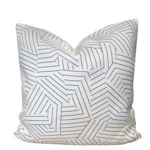 Puede incluir: Almohada blanca con un patr&oacute;n geom&eacute;trico azul de l&iacute;neas que forman formas abstractas.
