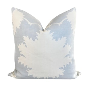 May include: A light blue throw pillow with a white floral pattern. The pillow is made of a soft, textured fabric.