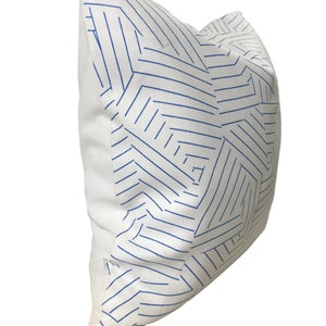 Puede incluir: Almohada blanca con un patr&oacute;n geom&eacute;trico azul. El patr&oacute;n est&aacute; formado por l&iacute;neas finas que crean una serie de tri&aacute;ngulos y cuadrados.