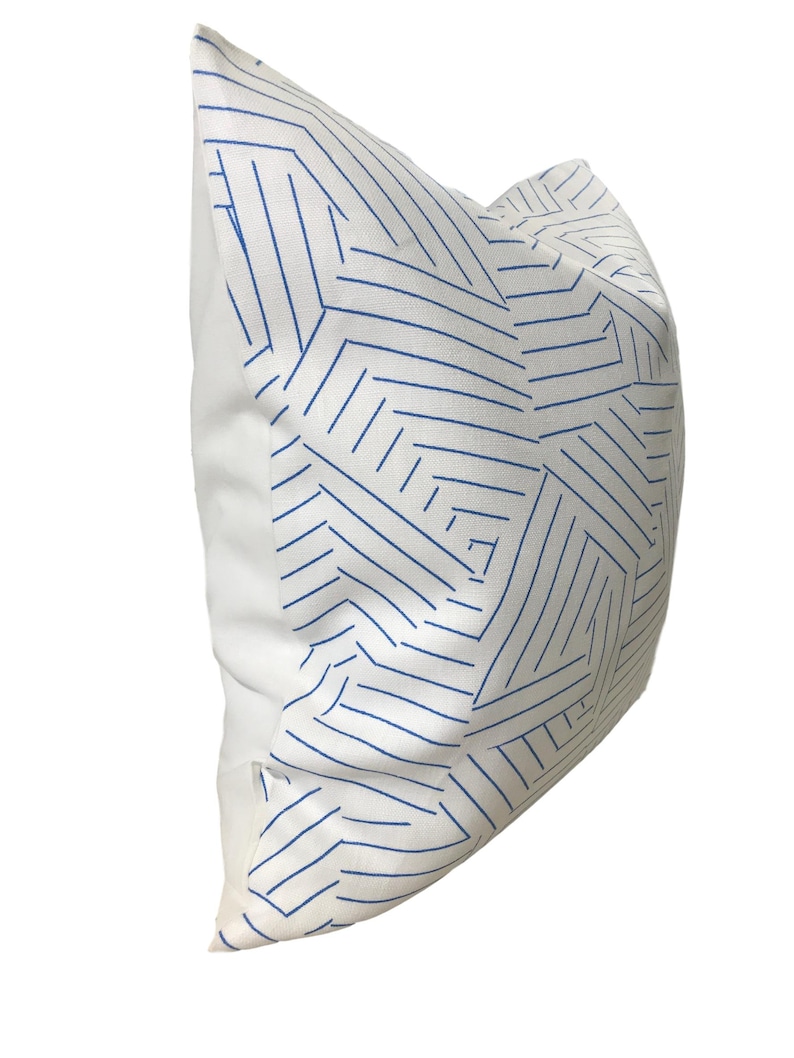 Puede incluir: Almohada blanca con un patr&oacute;n geom&eacute;trico azul. El patr&oacute;n est&aacute; formado por l&iacute;neas finas que crean una serie de tri&aacute;ngulos y cuadrados.