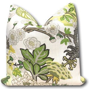 May include: A white pillow cover with a floral pattern featuring green leaves, white flowers, and yellow accents. The pattern is reminiscent of a traditional Asian design.