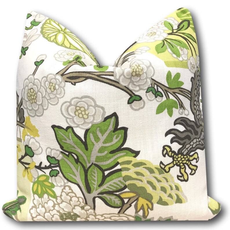 May include: A white pillow cover with a floral pattern featuring green leaves, white flowers, and yellow accents. The pattern is reminiscent of a traditional Asian design.