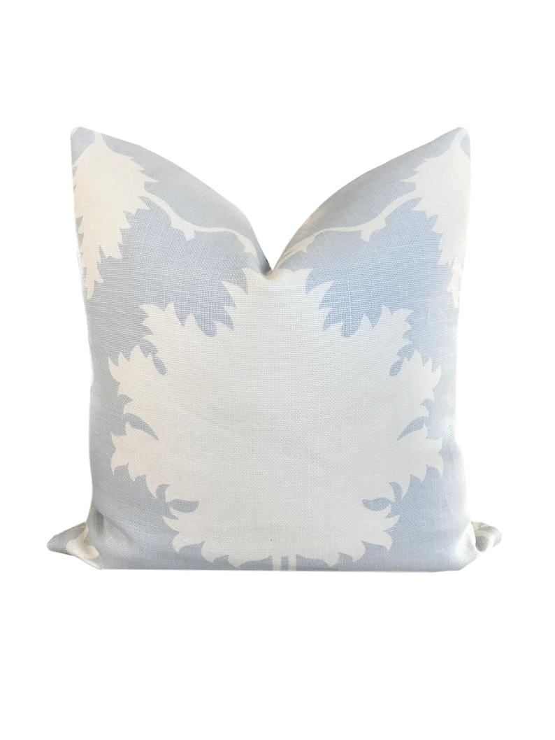 May include: A light blue throw pillow with a white floral pattern. The pillow is made of a soft, textured fabric.