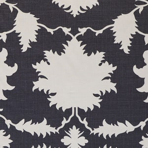 K&ouml;nnte beinhalten: Nahaufnahme eines Stoffes mit einem sich wiederholenden Muster. Das Muster zeigt gro&szlig;e, wei&szlig;e, stilisierte Blumen- und Blattformen vor einem dunkelblauen Hintergrund. Das Design ist symmetrisch und erzeugt eine visuell ansprechende Textur.