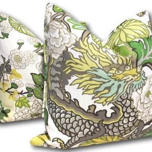 May include: Two decorative throw pillows with a white background and a floral pattern. One pillow features a green and yellow dragon design, while the other pillow features a more subtle floral pattern with green and yellow accents.