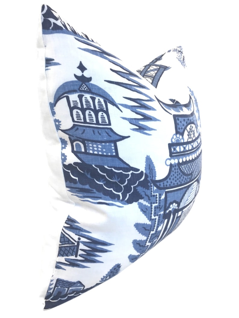 May include: Blue and white pillow cover with a traditional Chinese design featuring pagodas and stylized plants.