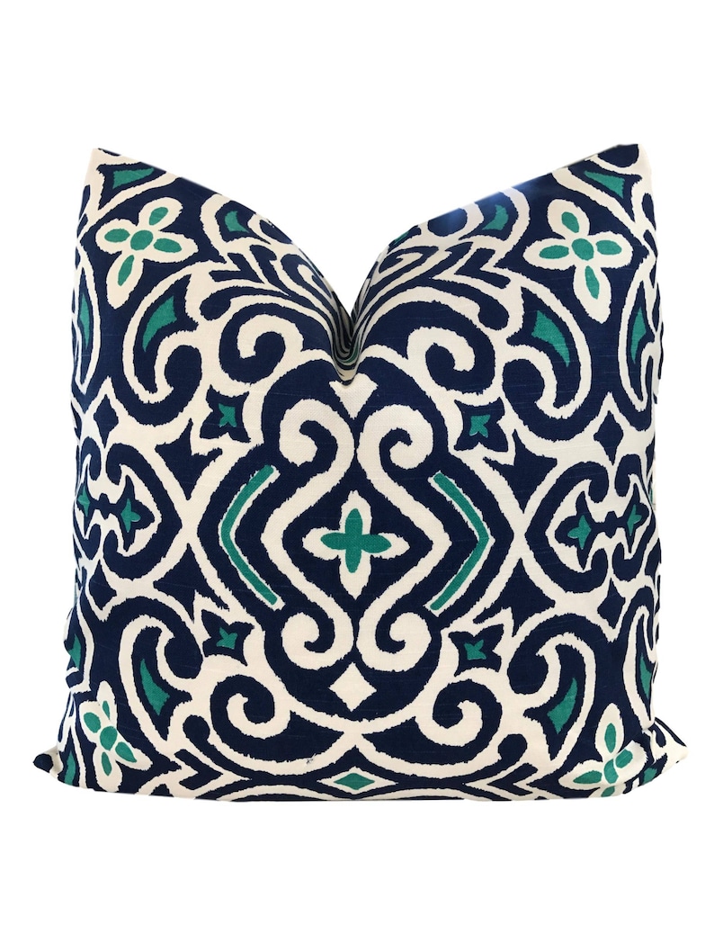 May include: A decorative throw pillow with a white background and a blue and teal geometric pattern.