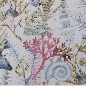 May include: A fabric with a repeating pattern of marine life. The design features coral in shades of pink and red, along with seashells, seaweed, and other aquatic plants in blue, green, and brown hues. The background is a light beige.