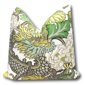 May include: A white pillow with a green, yellow, and gray dragon and floral pattern.