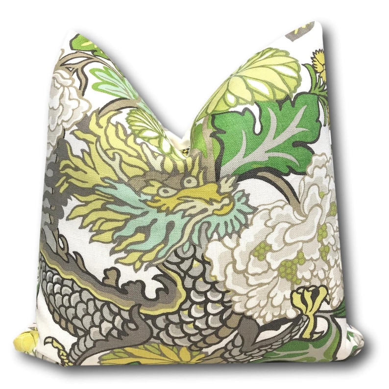 May include: A white pillow with a green, yellow, and gray dragon and floral pattern.