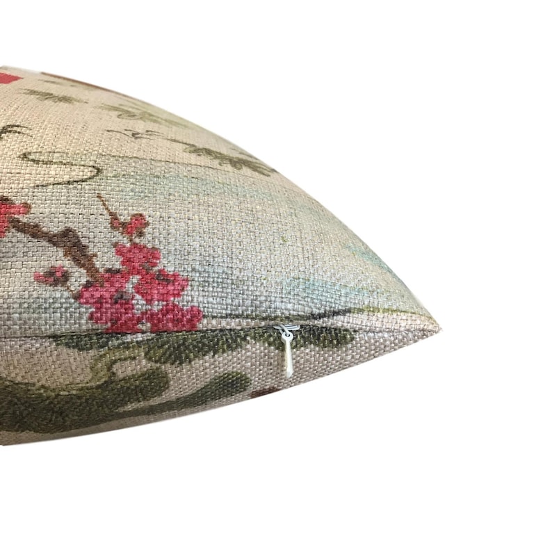Pode incluir: Uma almofada bege com um padr&atilde;o floral com flores cor-de-rosa e folhas verdes. A almofada tem um fecho de correr.