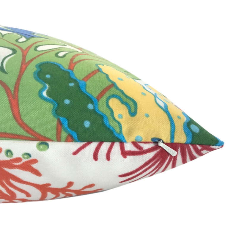 Puede incluir: Una almohada de tiro con estampado verde, amarillo, azul y rojo con una cremallera blanca.