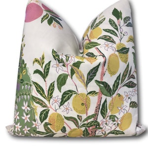 May include: A white pillow with a floral pattern featuring green leaves, pink and yellow fruit, and white flowers.