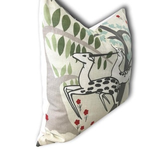 May include: A beige pillow with a white border features a stylized illustration of two deer in a forest setting. The deer are black and white with red flowers scattered throughout the design.