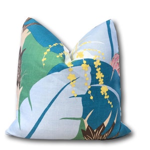 May include: A blue, green, and white throw pillow with a tropical leaf pattern. The pillow has yellow flowers and brown accents.