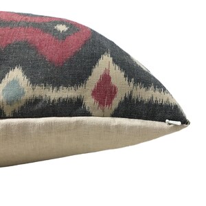 May include: A black, red, and cream patterned throw pillow with a zipper closure.