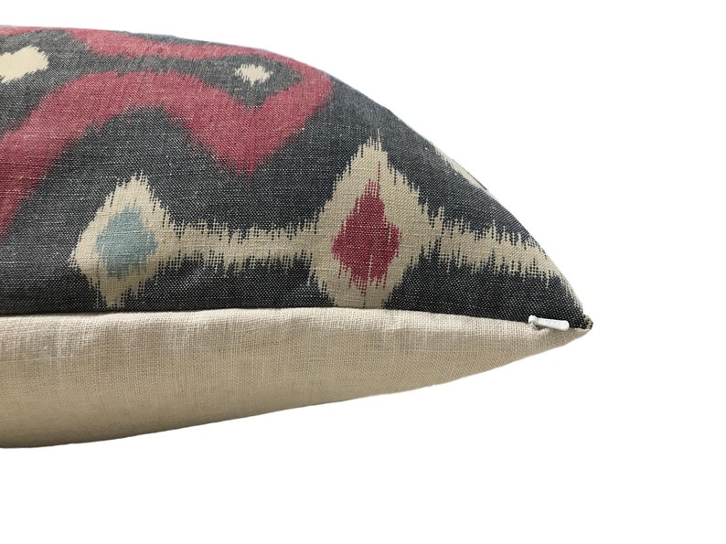 May include: A black, red, and cream patterned throw pillow with a zipper closure.