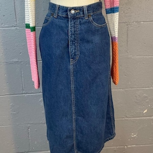Peut inclure: Ensemble deux pièces composé d'une jupe en jean bleu et d'un crop top en crochet coloré. Le haut a une encolure carrée et des manches longues avec des rayures roses, oranges, jaunes, vertes et blanches. La jupe est de longueur midi.