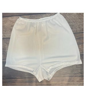 May include: White, high-waisted shorts made of a lightweight, possibly silky fabric. The shorts have a loose fit and a simple, classic design. The garment is clean and appears to be in good condition.