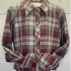 Peut inclure: Une chemise à carreaux à manches longues avec un devant boutonné. La chemise est un mélange de carreaux rouges, gris et blancs.
