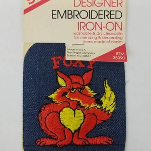 Könnte beinhalten: Aufbügelflicken mit gesticktem Design eines roten Fuchses mit gelbem Herz auf Jeansstoff. Der Flicken trägt die Aufschrift "FOX" und "DESIGNER EMBROIDERED IRON-ON". Waschbar und chemisch reinigbar, zum Ausbessern und Dekorieren von Jeansartikeln.