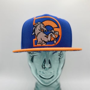 May include: A blue and orange baseball cap with a white horse logo and the text "L.E.F." on the front. The cap is on a mannequin head.