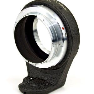 May include: A black and silver camera lens adapter with the text "K/AR GERMANY 49.5MM" on the side.