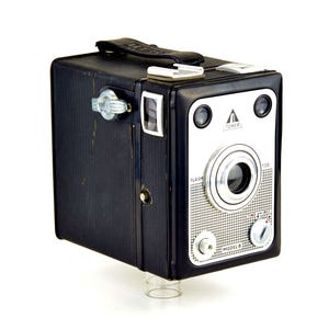 May include: A black Tower Model 8 camera with a silver lens and controls. The camera has a built-in flash and a 120 film setting.