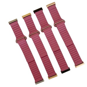 Peut inclure: Quatre bracelets de montre en silicone rose avec des fermoirs m&eacute;talliques de diff&eacute;rentes couleurs. Les bracelets ont une texture c&ocirc;tel&eacute;e et sont con&ccedil;us pour les montres intelligentes.