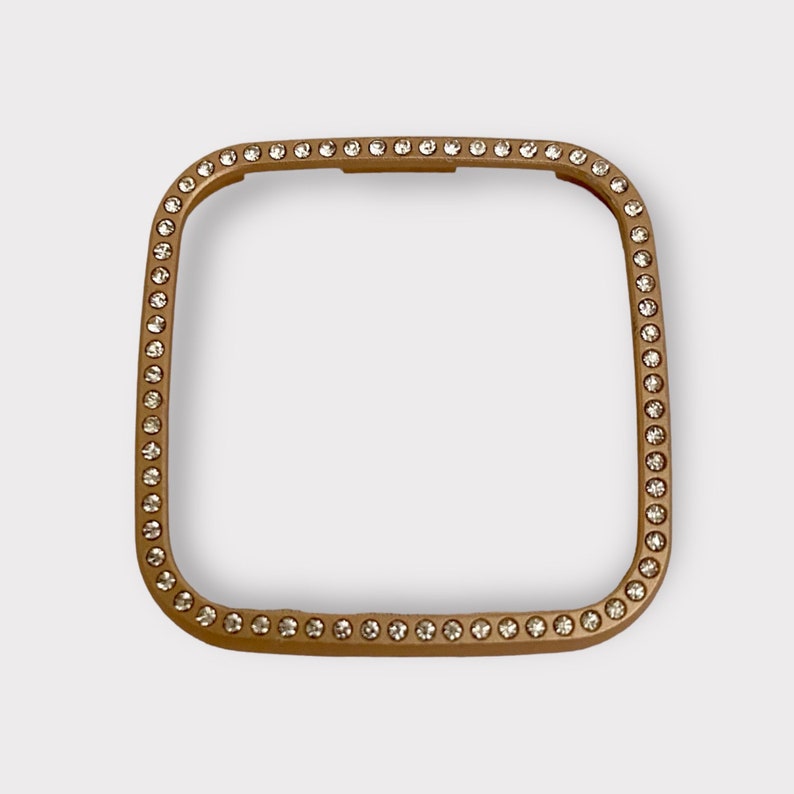 May include: A gold-toned square watch band with a clear rhinestone border.