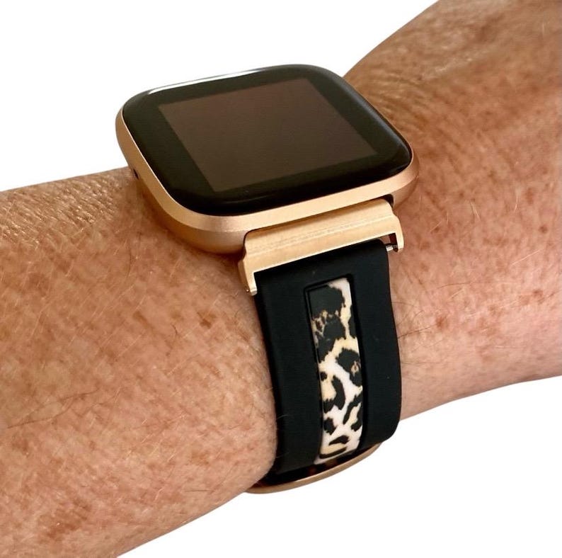 Op de afbeelding: Een smartwatch in ros&eacute; goud met een zwart siliconen bandje met luipaardprint.