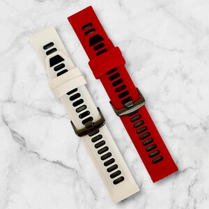 Pu&ograve; includere: Due cinturini per orologio, uno rosso e uno bianco, con accenti neri. Entrambi i cinturini hanno una fibbia in metallo.