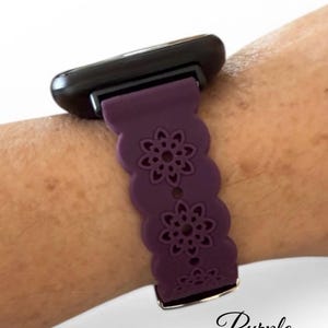 May include: A purple watch band with a floral design. The band is attached to a black watch face. The word "Purple" is written in cursive at the bottom of the image.