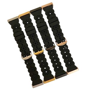 May include: Four black watch bands with floral cutouts and various metal clasps. The clasps are in silver, gold, bronze, and rose gold tones. The bands are made of a flexible material.