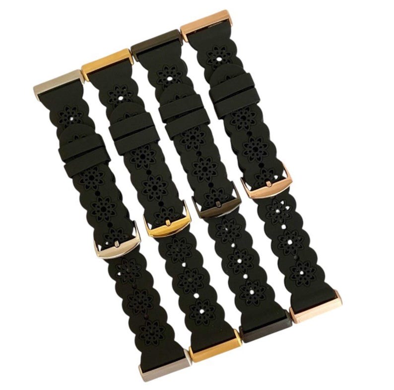 May include: Four black watch bands with floral cutouts and various metal clasps. The clasps are in silver, gold, bronze, and rose gold tones. The bands are made of a flexible material.