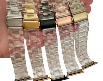 May include: Five clear plastic watch bands with different colored metal clasps. The clasps are silver, gold, black, rose gold, and gold. The bands are all the same style and have a clear, textured finish.
