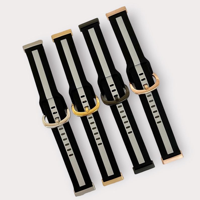 May include: Five different watch bands with black and silver stripes. The bands have different colored buckles: rose gold, gold, silver, and black.