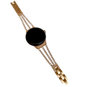 Pu&ograve; includere: Un orologio color oro con quadrante nero e cinturino a catena a tre file decorato con strass trasparenti.