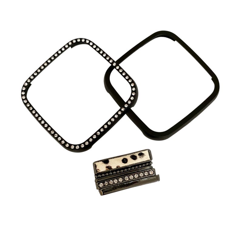 May include: Two black square watch face bezels with a row of clear rhinestones around the edge. One bezel is plain and the other has a black and white animal print band with clear rhinestones.