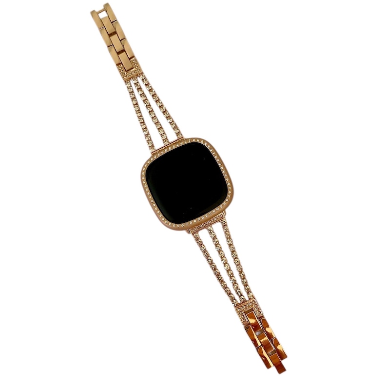 K&ouml;nnte beinhalten: Ein goldfarbenes Armband mit schwarzem Zifferblatt und einer Reihe von klaren Strasssteinen am Rand. Das Armband besteht aus mehreren Reihen von miteinander verbundenen Metallteilen, die jeweils mit einem Strassstein besetzt sind.